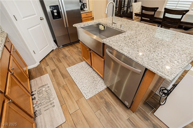 kitchen featuring a sink, brown cabinets, stainless steel appliances, and light wood-style floors