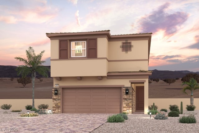 view of front facade with a garage, a mountain view, decorative driveway, stone siding, and stucco siding