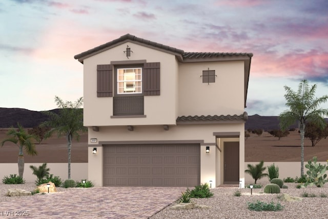 mediterranean / spanish-style home with decorative driveway, a tile roof, a garage, and stucco siding