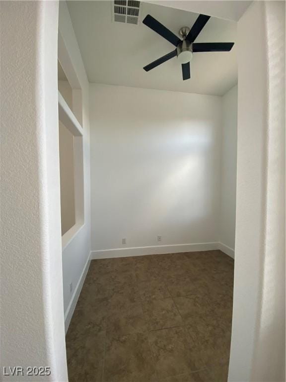 empty room featuring visible vents, a ceiling fan, and baseboards
