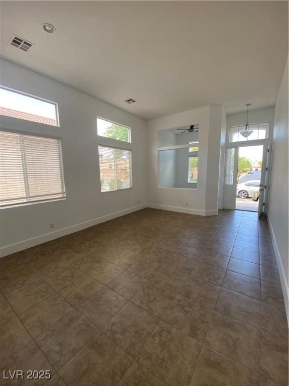 spare room with visible vents, dark tile patterned flooring, and baseboards