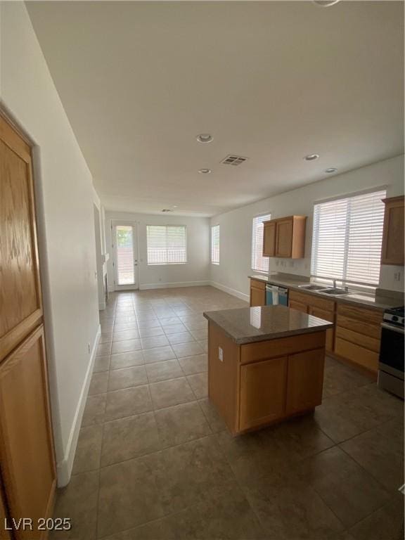 kitchen with appliances with stainless steel finishes, baseboards, a center island, light tile patterned flooring, and recessed lighting