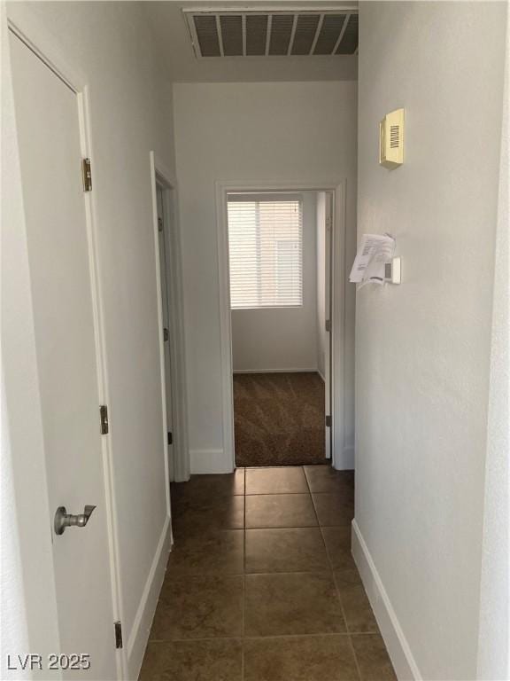 hallway featuring tile patterned floors, carpet, visible vents, and baseboards