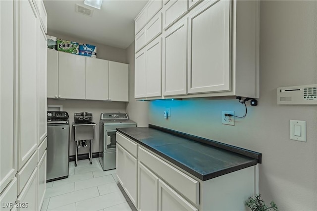 clothes washing area with visible vents, washer and dryer, cabinet space, and light tile patterned flooring