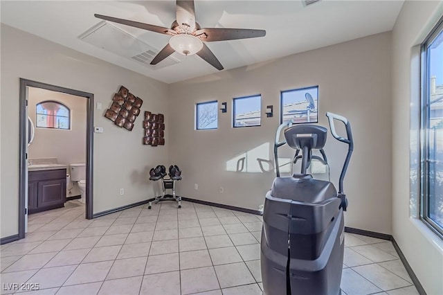 exercise room featuring light tile patterned flooring, a ceiling fan, baseboards, and plenty of natural light