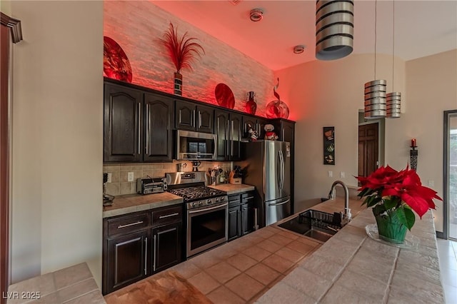kitchen featuring decorative backsplash, a sink, appliances with stainless steel finishes, tile countertops, and tile patterned flooring