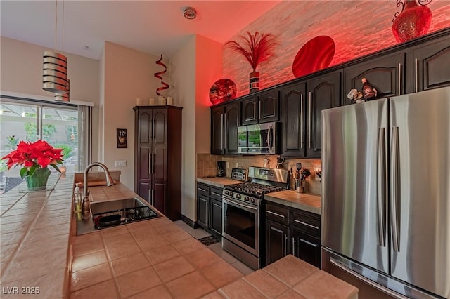 kitchen featuring stainless steel appliances, a high ceiling, tile countertops, and a sink