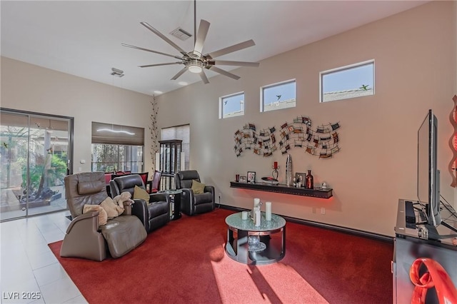 living area with a towering ceiling, a ceiling fan, carpet flooring, and visible vents