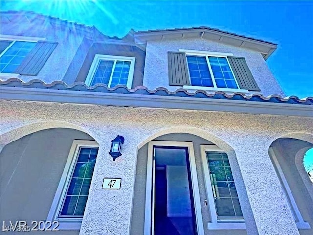 exterior space featuring stucco siding and a tiled roof