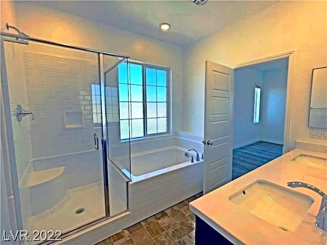 bathroom featuring double vanity, a garden tub, a stall shower, and a sink