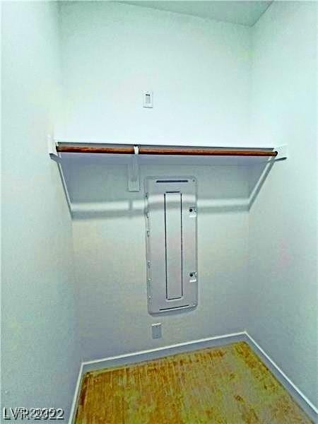clothes washing area with electric panel and baseboards