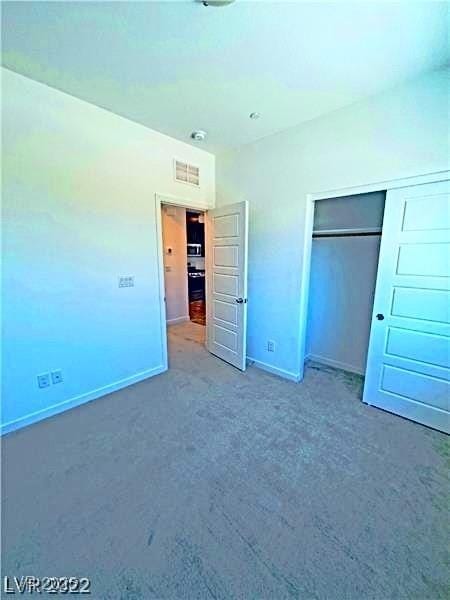 unfurnished bedroom featuring baseboards, carpet floors, and a closet