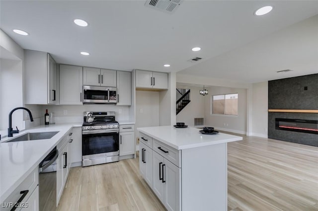 kitchen featuring visible vents, stainless steel appliances, light wood-type flooring, and a sink