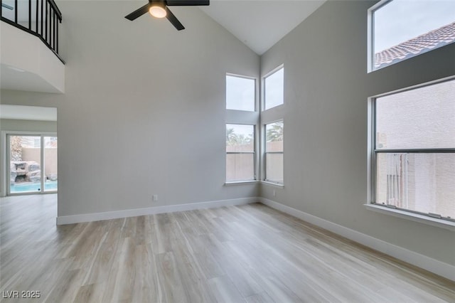 empty room featuring a ceiling fan, high vaulted ceiling, wood finished floors, and a healthy amount of sunlight