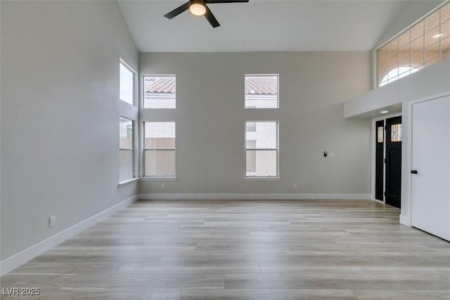unfurnished living room with a wealth of natural light, high vaulted ceiling, ceiling fan, and light wood-style floors