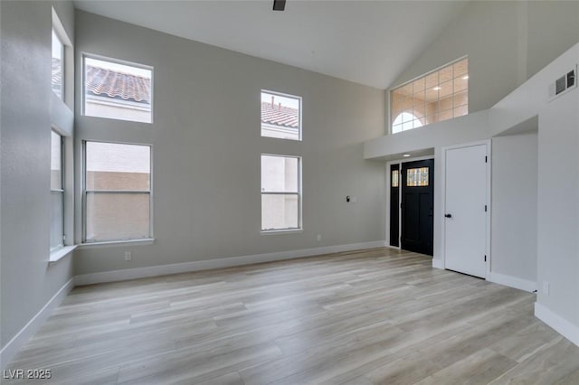 foyer featuring visible vents, light wood-style floors, high vaulted ceiling, and baseboards