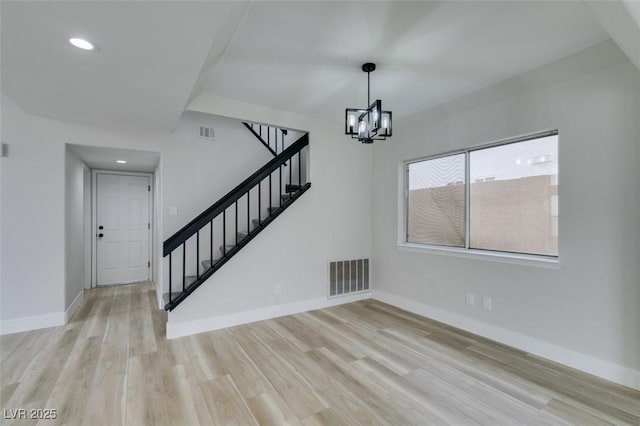 interior space with visible vents, wood finished floors, an inviting chandelier, and stairs