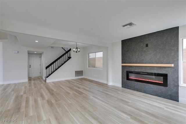 unfurnished living room featuring visible vents, wood finished floors, a fireplace, and stairway