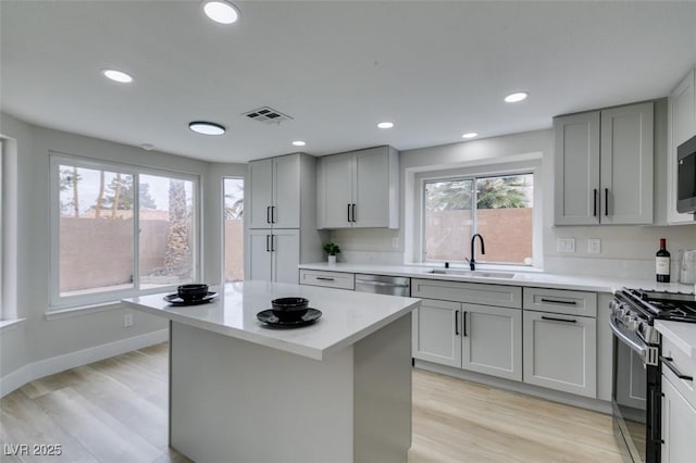 kitchen with a sink, visible vents, gray cabinetry, stainless steel appliances, and light countertops
