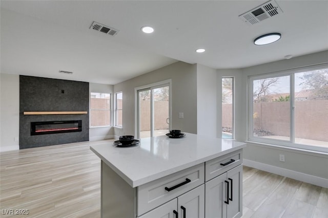 kitchen with a large fireplace, visible vents, and light countertops