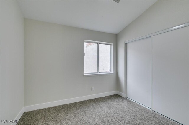 unfurnished bedroom featuring lofted ceiling, carpet flooring, and baseboards