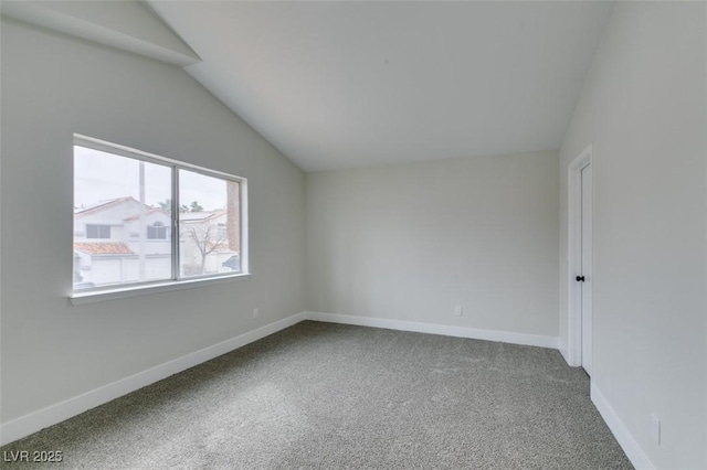 carpeted empty room with vaulted ceiling and baseboards