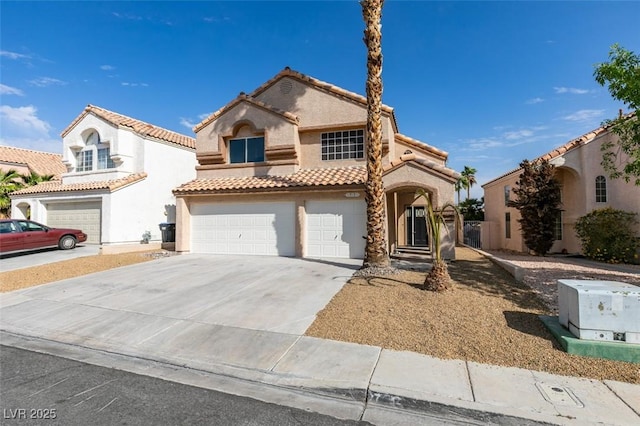 mediterranean / spanish house featuring stucco siding, a tiled roof, concrete driveway, and an attached garage