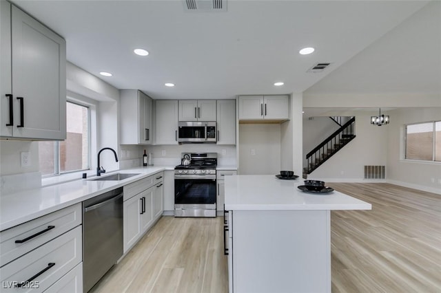 kitchen with light wood finished floors, a sink, stainless steel appliances, and visible vents