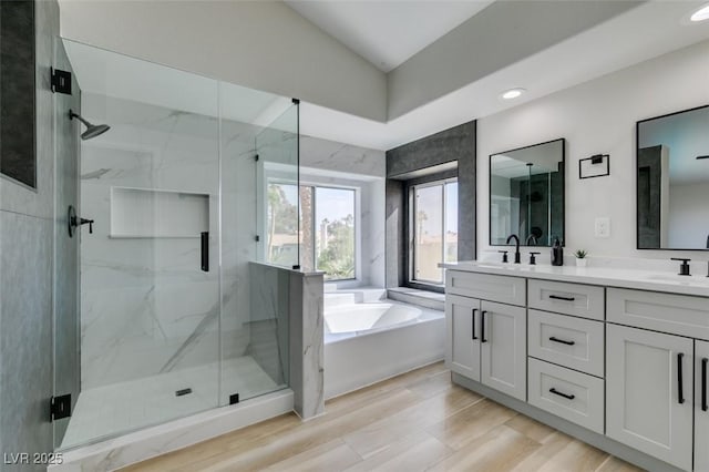 bathroom featuring a garden tub, a marble finish shower, a sink, and double vanity