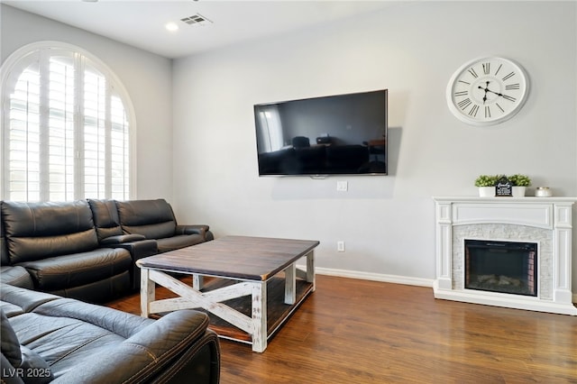 living room with a stone fireplace, visible vents, wood finished floors, baseboards, and recessed lighting