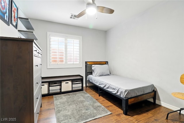 bedroom with visible vents, a ceiling fan, baseboards, and wood finished floors