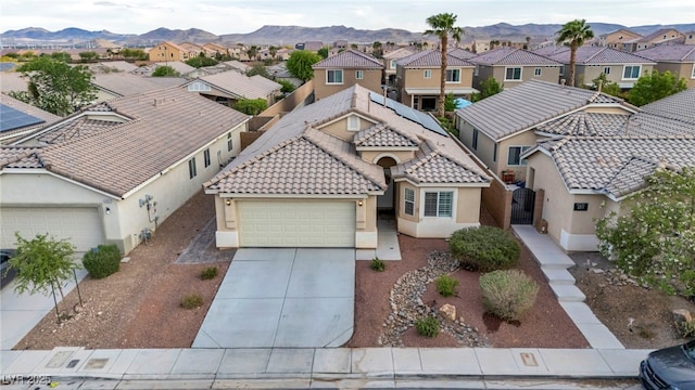 view of front facade featuring driveway, a residential view, a garage, a mountain view, and stucco siding