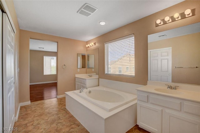 8988 Winchester Ridge St, Las Vegas, NV 89139 - bathroom with visible vents, two vanities, a bath, and a sink