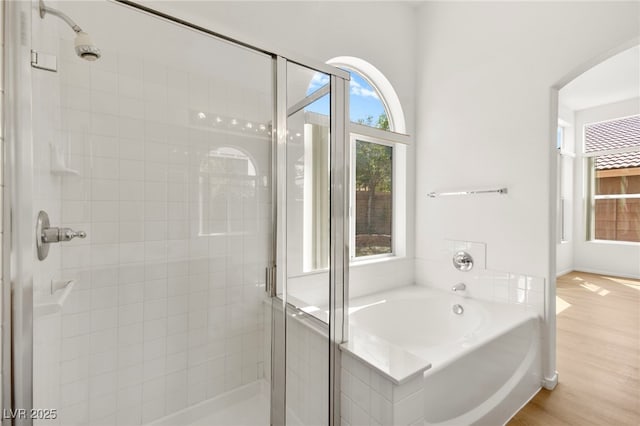 bathroom with wood finished floors, a garden tub, and a stall shower