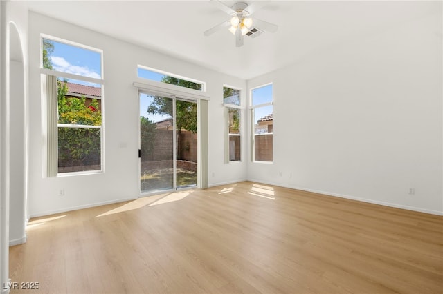 spare room featuring visible vents, a ceiling fan, plenty of natural light, and light wood-type flooring
