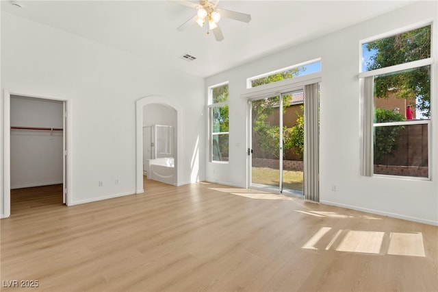 unfurnished bedroom with visible vents, arched walkways, baseboards, light wood finished floors, and access to outside