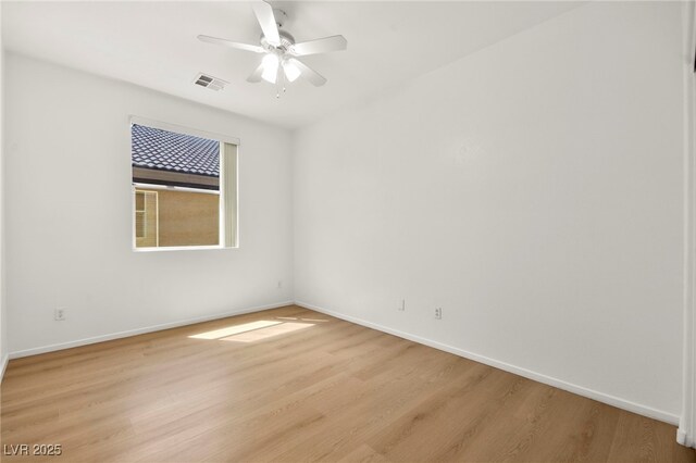 spare room featuring baseboards, ceiling fan, light wood-style flooring, and visible vents