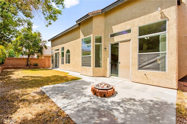 back of property featuring fence, stucco siding, an outdoor fire pit, and a patio area