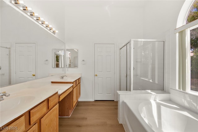 full bathroom featuring wood finished floors, a sink, a towering ceiling, and a stall shower