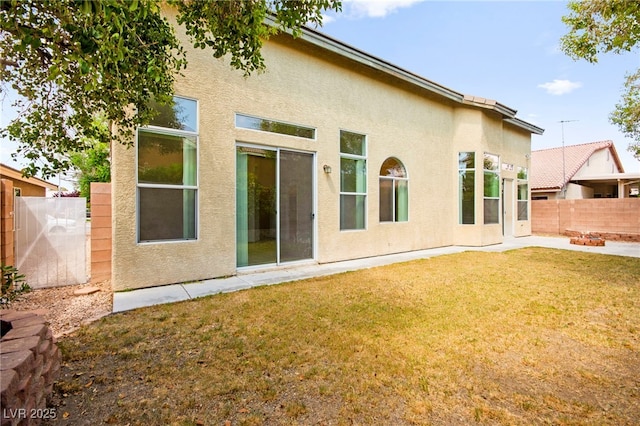 back of house with a lawn, a fenced backyard, and stucco siding