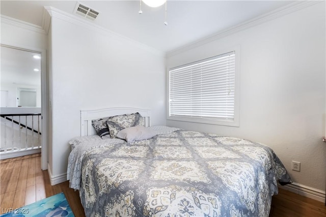 bedroom with visible vents, ornamental molding, and wood finished floors