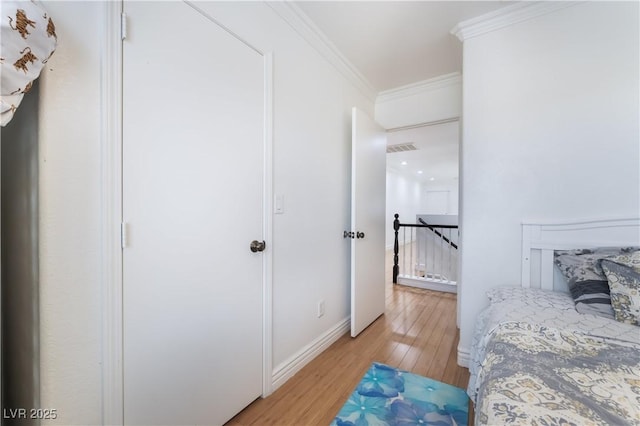 bedroom featuring light wood-style floors, baseboards, ornamental molding, and visible vents