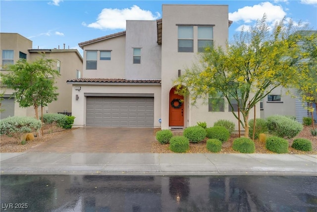 view of front facade featuring an attached garage, stucco siding, driveway, and a tile roof