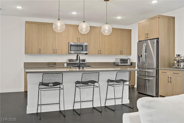 kitchen featuring light brown cabinets, recessed lighting, a toaster, a kitchen bar, and stainless steel appliances