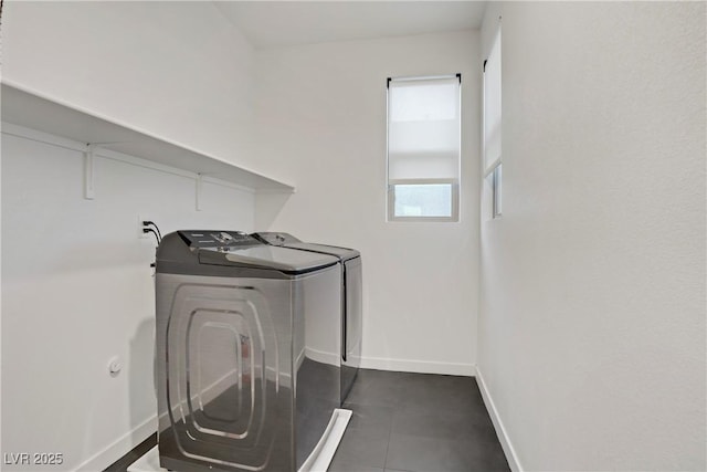 clothes washing area with washing machine and clothes dryer, baseboards, dark tile patterned flooring, and laundry area