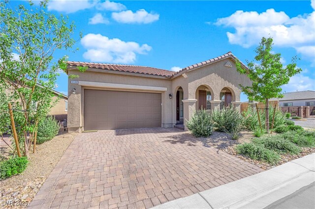 9590 Smiley Creek St, Las Vegas, NV 89178 - mediterranean / spanish-style home featuring a garage, stucco siding, a tile roof, and driveway