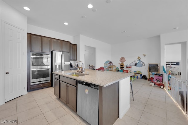 9590 Smiley Creek St, Las Vegas, NV 89178 - kitchen with light tile patterned floors, stainless steel appliances, an island with sink, and a sink