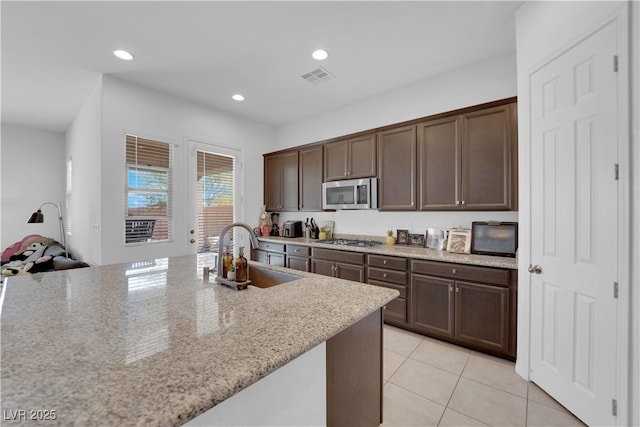 9590 Smiley Creek St, Las Vegas, NV 89178 - kitchen with light tile patterned floors, appliances with stainless steel finishes, dark brown cabinets, a sink, and visible vents