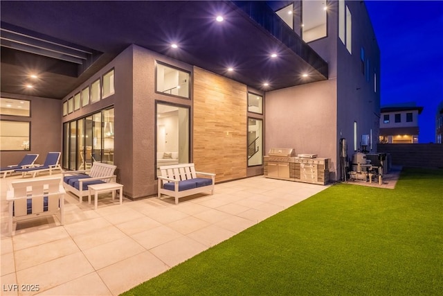 back of house at twilight with stucco siding, a yard, fence, a patio, and exterior kitchen