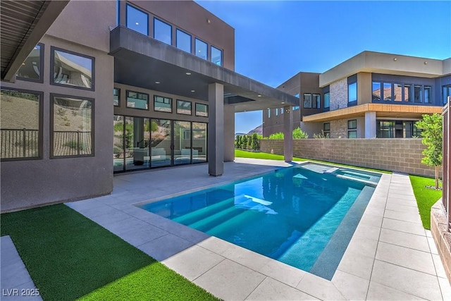 view of swimming pool with fence, a patio, and a pool with connected hot tub